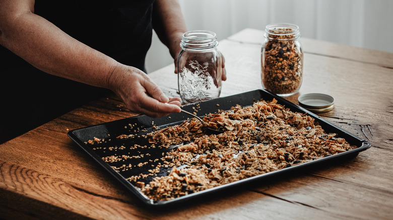 Person scooping toasted oats into jar