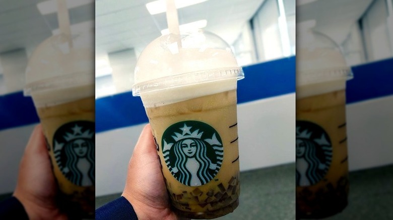 Person holding latte with coffee jelly