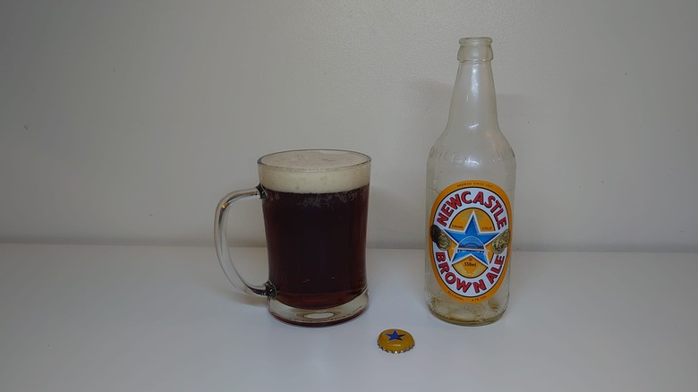 An empty bottle of Newcastle Brown Ale with a full glass next to it