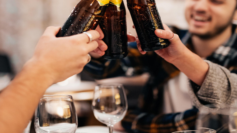 A group of friends clinking bottles of Cobra together