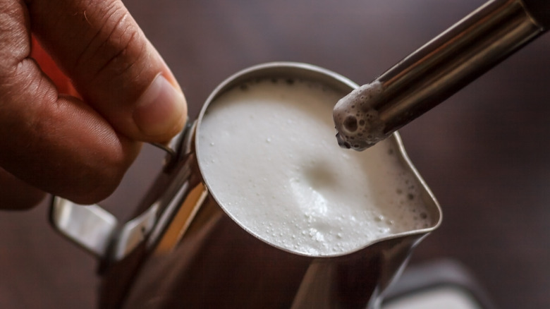 Hands steaming milk