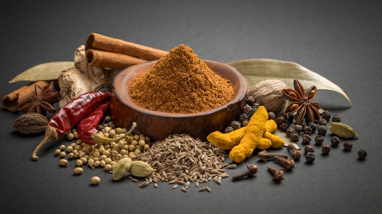 Ground garam masala in a bowl surrounded by whole spice