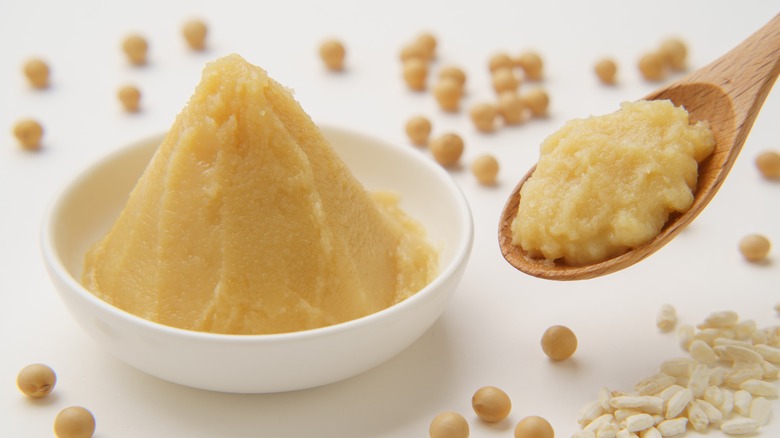 White miso mounded in a white bowl and on a wooden spoon