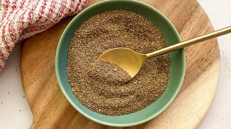 Homemade Old Bay Seasoning in green bowl with golden spoon