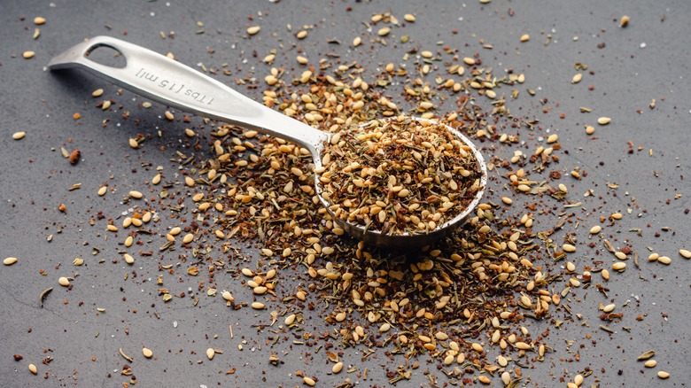 Za'atar seasoning in a tablespoon and scattered on countertop