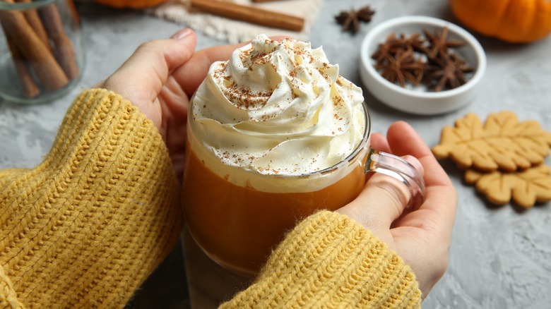 Hands holding mug of pumpkin spice latte