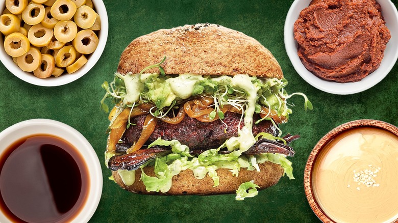 Veggie burger surrounded by various ingredients against a green background