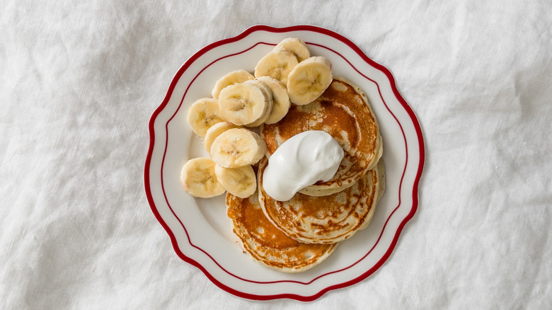 Greek yogurt is dolloped on some pancakes.