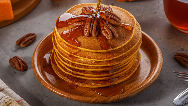 A stack of pancakes is covered in syrup.