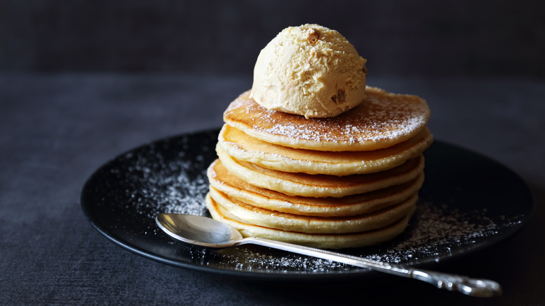 Pancakes are topped with a scoop of ice cream.