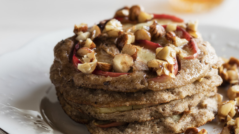 Nuts sit atop pancakes with fruit.