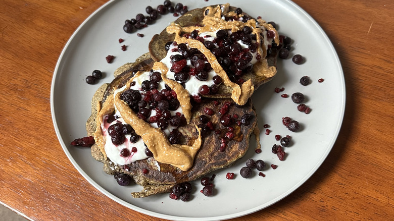 Peanut butter is spread on some pancakes with other toppings.