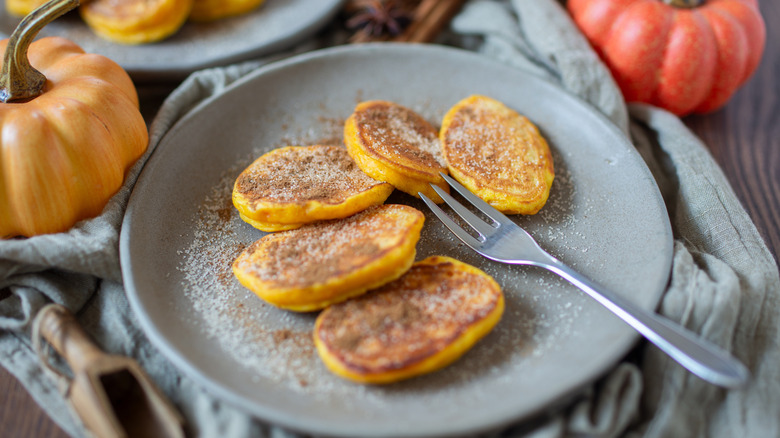 Pancakes on a plate are covered with cinnamon sugar.