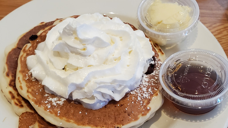 Pancakes are covererd in whipped cream.