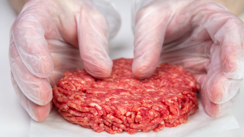 Shaping burger patty with gloves