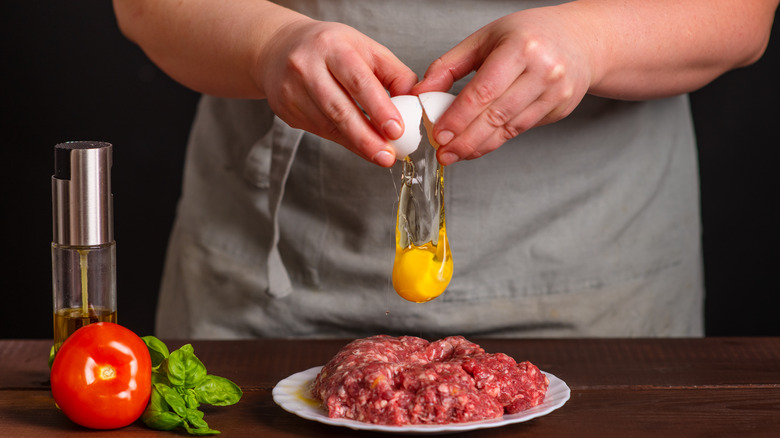 Cracking egg onto ground beef