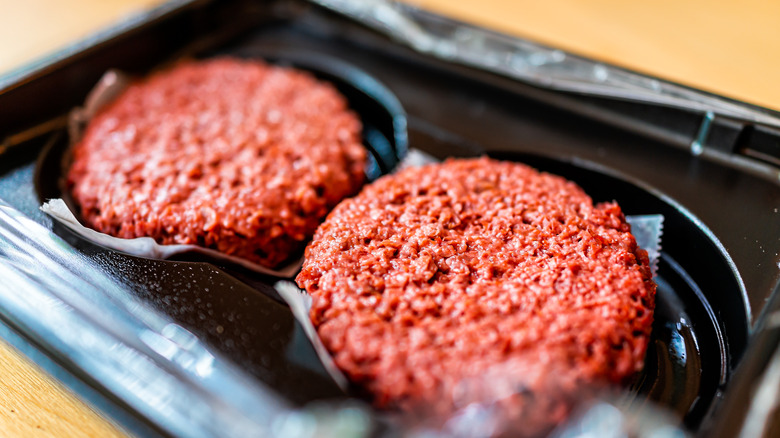 Uncooked beef burgers in container 