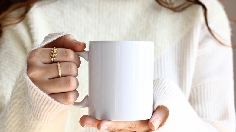 Person wearing sweater holding mug