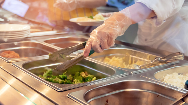 Gloved hands over buffet trays