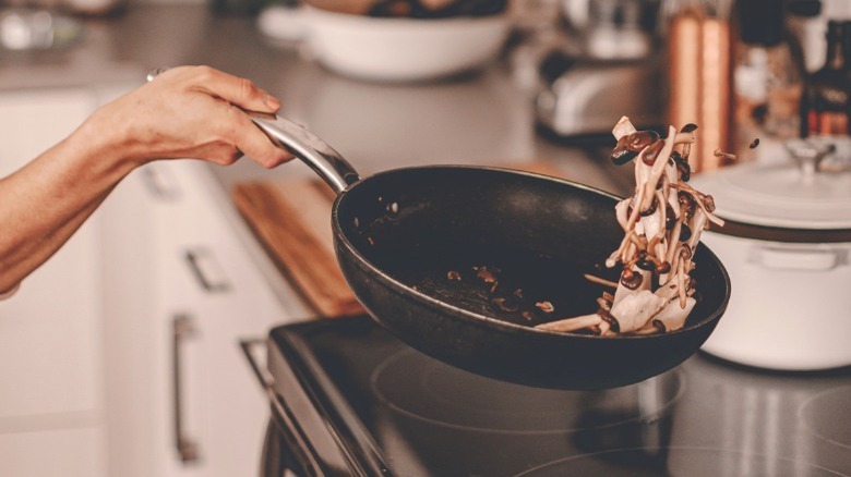 Person frying mushrooms in a skillet