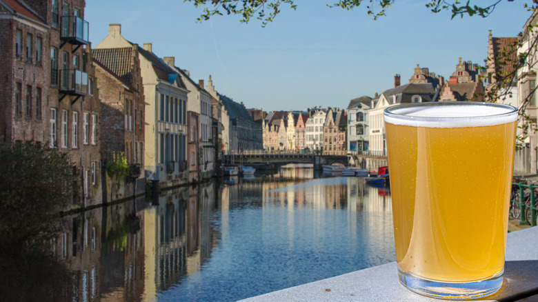 Belgian beer against the backdrop of buildings and canal in Ghent