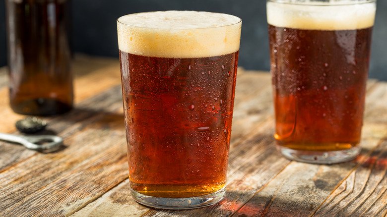 Two pint glasses of brown ale on a table