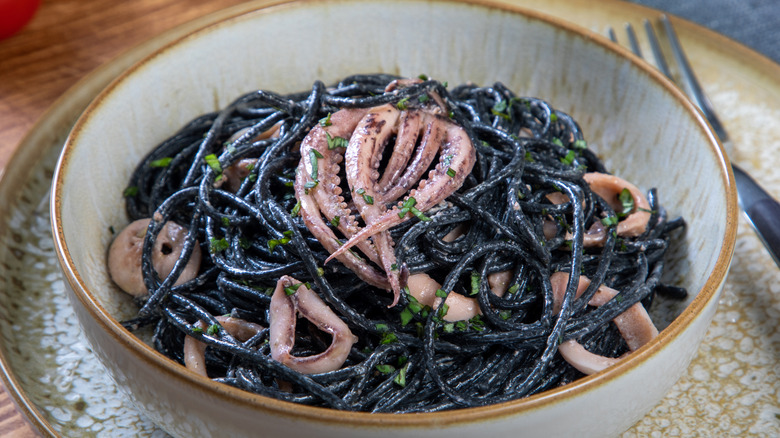 cuttlefish ink pasta in a bowl with calamari rings