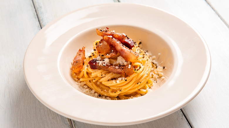 spaghetti alla gricia in white bowl topped with guanciale