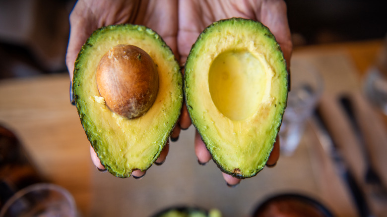 Avocado halves in hand