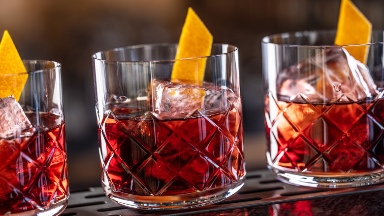 Three Negroni cocktails on a metal bar