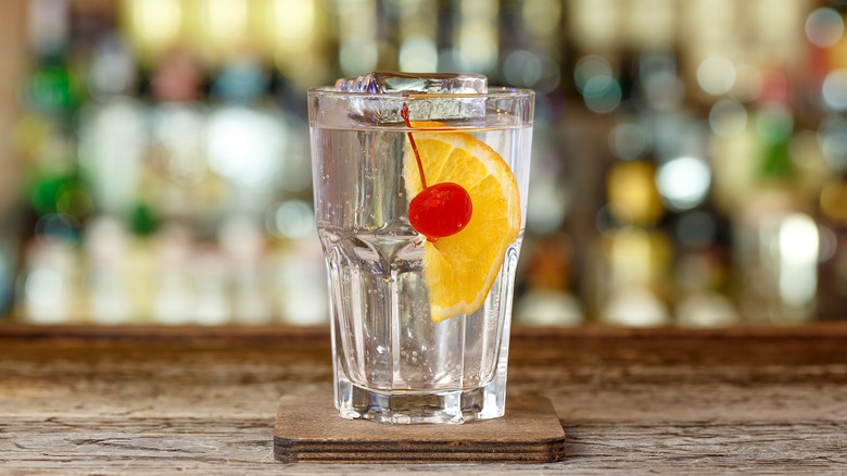 Tom Collins cocktail with a cherry and orange garnish