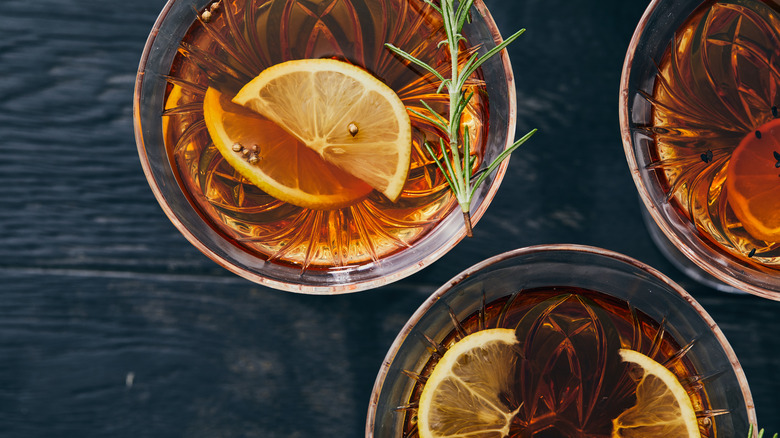 Three bourbon cocktails with lemon and rosemary garnishes