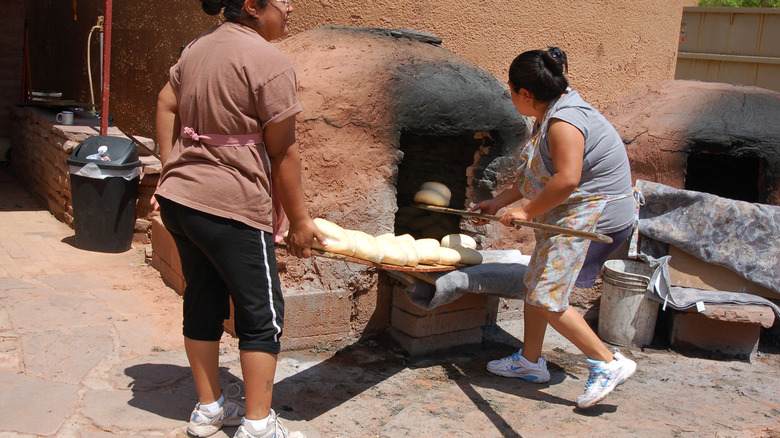 Women cooking pueblo bread horno