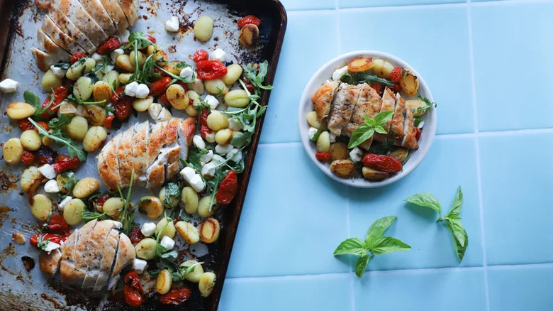 Sheet-Pan Caprese Chicken Gnocchi on white tile with basil