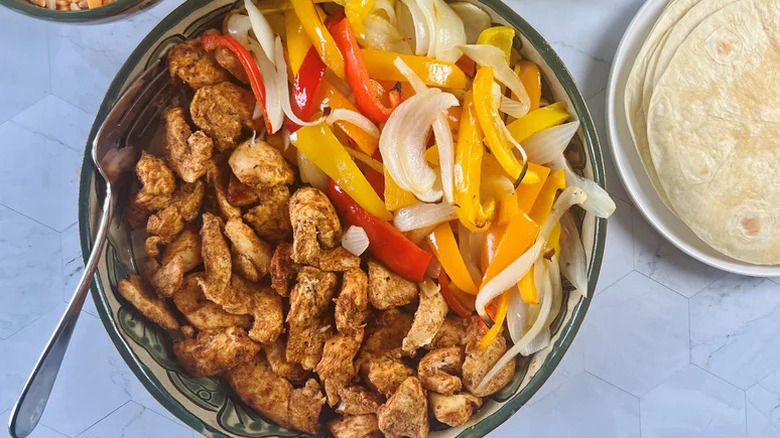 Sheet-Pan Chicken Fajitas with Spicy Avocado Crema in silver bowl with tortillas