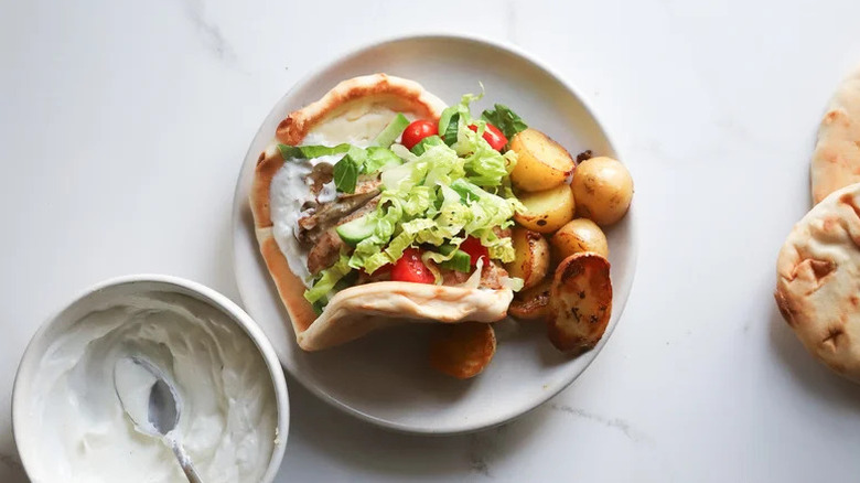 Sheet Pan Chicken Shawarma with Lemon-Rosemary Potatoes on white plate with sauce
