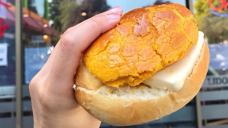 person holding pineapple bun with butter