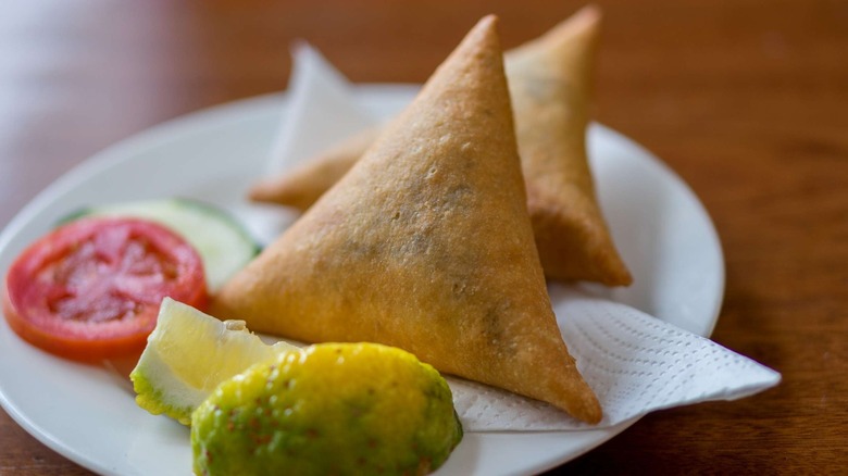 Samosas with tomato, cucumber, and lime