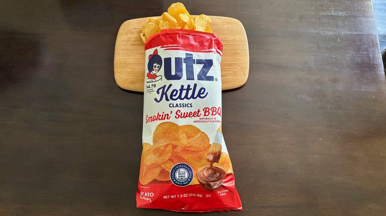 Open bag Utz kettle Smokin' Sweet BBQ Chips spilling onto cutting board