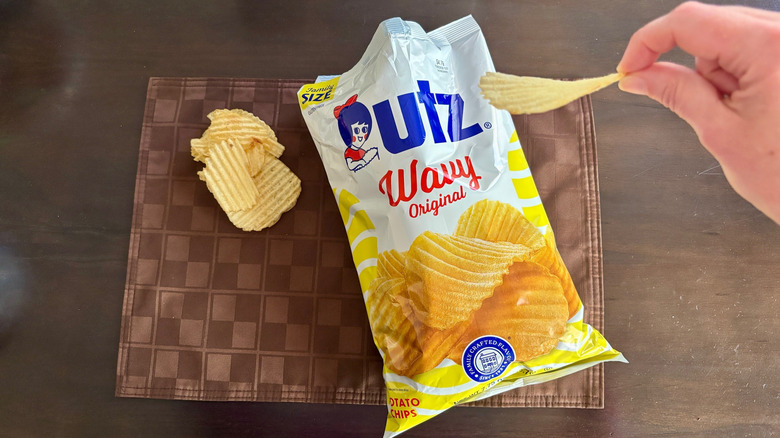 Fingers holding Wavy Original chip over open bag