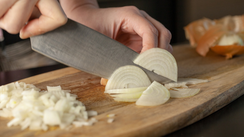 Knife dicing onion on board