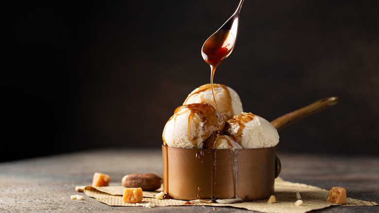 spoon pouring caramel onto ice cream