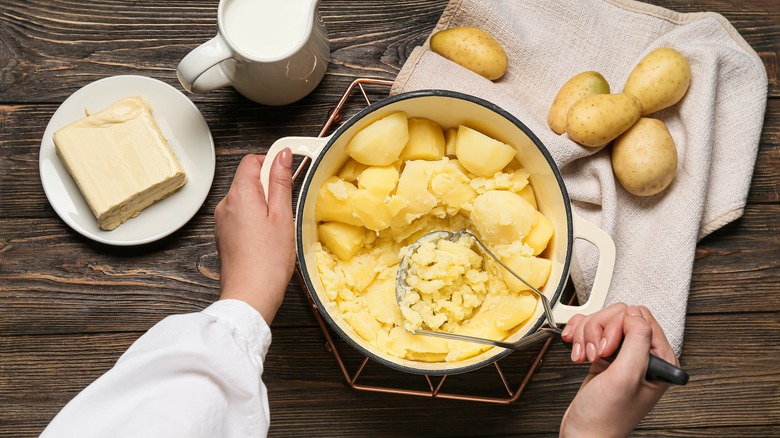 Person mashing potatoes in pan