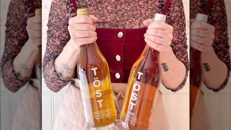 hands holding two bottles of TÖST wines