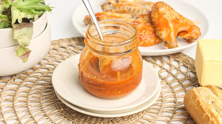 Open jar of Buffalo sauce with wings