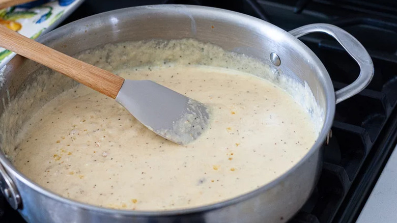Creamy Alfredo sauce being cooked in saucepan