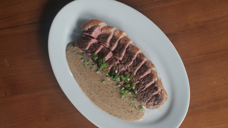 Sliced steak with peppercorn sauce and sliced green onions