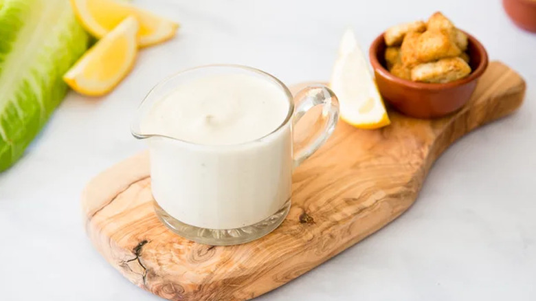 Small jug of Caesar sauce on wooden serving board