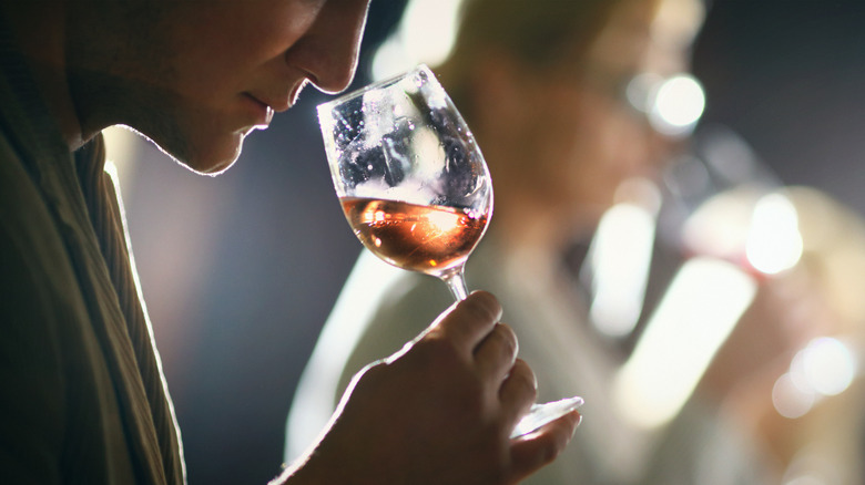 person closely smelling wine glass