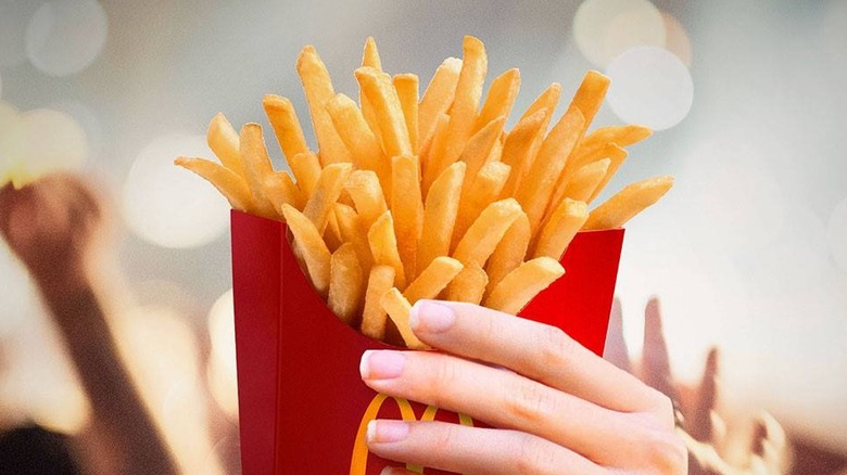 hand holding carton of fries